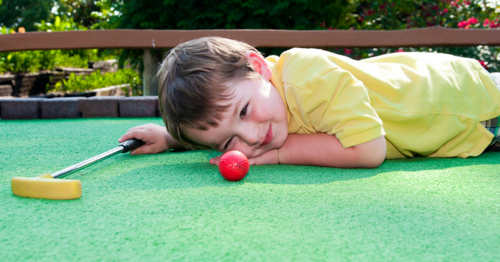 Little boy playing mini-golf